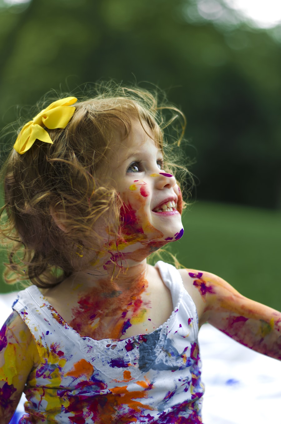A joyful child playing, covered in colourful paint